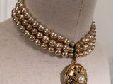 pearl and gold necklace with a medallion pendant on a mannequin