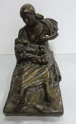une vieille statue en bronze représentant une femme tenant un bébé sur ses genoux