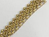 a close up of a gold bracelet on a white surface