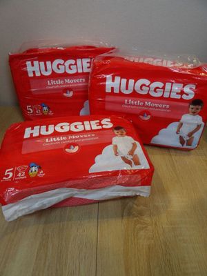 three packs of huggies diapers sitting on top of a wooden table