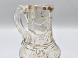 an old glass pitcher with a gold rim on a white surface