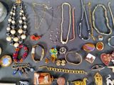 many different necklaces and bracelets laid out on a table