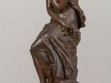 an image of a bronze statue of a woman sitting on top of a wooden table