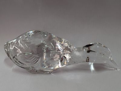 une figurine d'oiseau en verre transparent posée sur une surface blanche