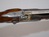 a close up of a gun with a wooden handle on a white surface