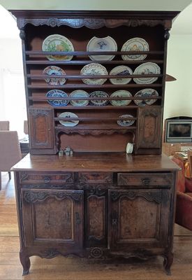 a wooden china cabinet with many plates on top of it