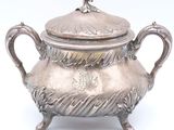 une théière en argent avec un couvercle, posée sur un socle