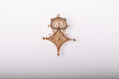 un pendentif en or orné d'une horloge, posé sur une surface blanche