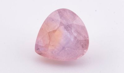 une pierre de quartz rose en forme de larme posée sur une surface blanche