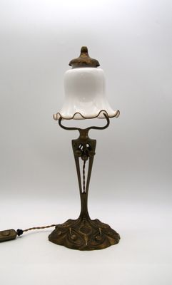une lampe à l'ancienne surmontée d'un abat-jour en verre blanc