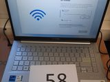 un ordinateur portable posé sur une table, sur laquelle se trouve une pancarte