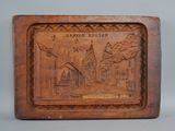 an old wooden plaque with a picture of a town on it