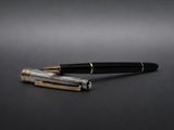 un stylo noir et doré posé sur une surface noire
