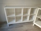 a white bookcase with several shelves in the corner