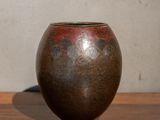 a brown vase sitting on a table with a white wall in the background