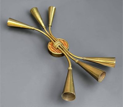a close up of a brass wall light with five brass cones