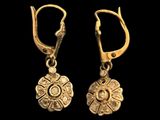 a pair of gold earrings on a black background