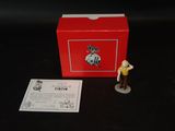 une petite figurine d'un homme debout à côté d'une boîte rouge