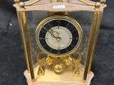 a gold clock with a glass case on a black background