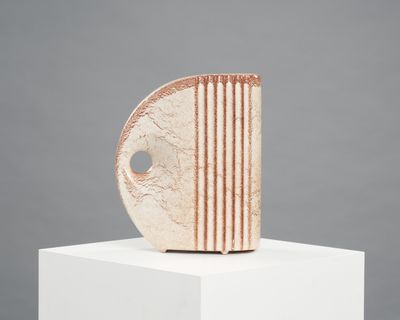 une sculpture abstraite posée sur un socle blanc, avec un fond gris