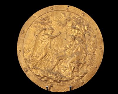 une image représentant une assiette en or sur laquelle figurent une femme et un chien