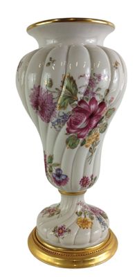 un vase blanc orné de fleurs roses, posé sur un socle doré