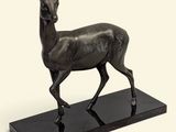 une image représentant une statue en bronze d'un cerf posée sur un socle noir