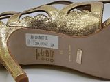 pair of women ' s gold shoes with a label on the heel