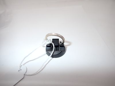 une photo en noir et blanc d'une bague posée sur une surface blanche