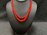 a red beaded necklace and matching earrings on a mannequin