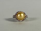yellow pearl and diamond ring on a white surface