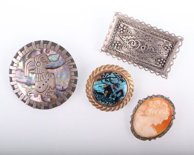 trois broches en argent et deux broches à camée sur un fond blanc