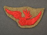 an embroidered patch with a red bird on it on a gray surface