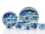 Plusieurs assiettes et tasses bleues et blanches sont posées sur une surface blanche