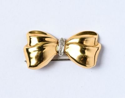 broche en forme de nœud en or sertie de diamants sur fond blanc