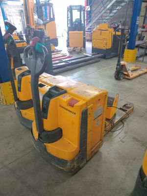 yellow forklifts are lined up in a warehouse with other forklifts in the background