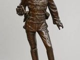une statue en bronze représentant un homme debout au sommet d'un rocher