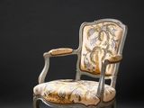 une vieille chaise avec un dossier et des accoudoirs tapissés de fleurs