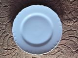 a white plate sitting on a brown table cloth