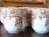 three cups sitting on a table with plates in the background