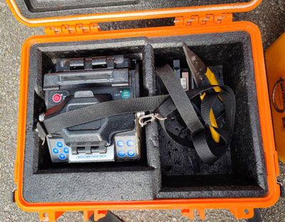 une mallette orange contenant des outils, posée par terre