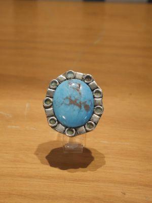 Bague en turquoise avec des touches d'argent, posée sur une table en bois
