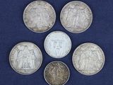 six pièces d'argent de tailles et de formes différentes sur fond bleu