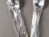 two silver spoons wrapped in plastic on a table