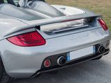 the rear end of a silver sports car parked on the side of the road