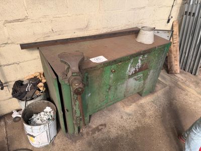 un coffre vert posé dans un garage, à côté d'une poubelle