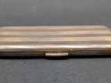an old silver cigarette case sitting on top of a black table