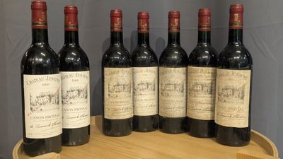 six bouteilles de vin rouge sont alignées sur un tonneau en bois