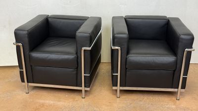 pair of black leather lounge chairs with chrome legs