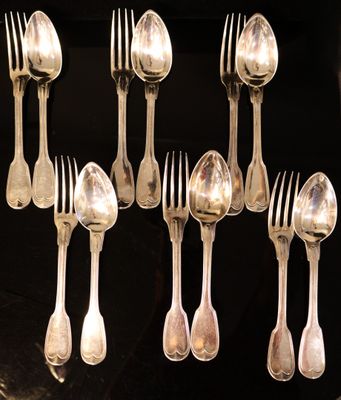 a lot of silver spoons and forks on a black table